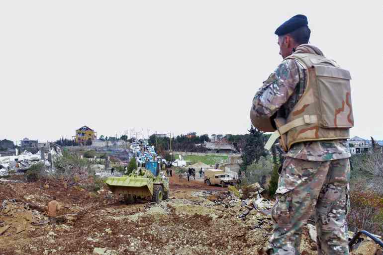 doc-36xg3ud-1739192772 A Lebanese soldier stands guard after army deployment as a bulldozer opens a road for the residents of the southern village of Rubb Thlathin to return to their town on February 9, 2025. (Photo by Fadel ITANI / AFP)