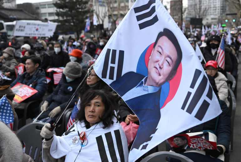 doc-36yk7ff-1740494703 A supporter of South Korea President Yoon Suk Yeol waves a flag showing a picture of Yoon during a rally near the Constitutional Court in Seoul on February 25, 2025, as Yoon is scheduled to attend his final impeachment hearing. (Photo by Jung Yeon-je / AFP)