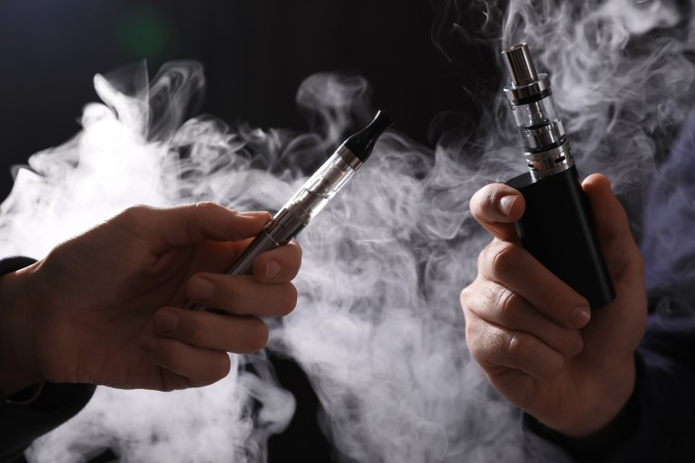 shutterstock_2118000068-1715758951 People with electronic cigarettes on black background, closeup