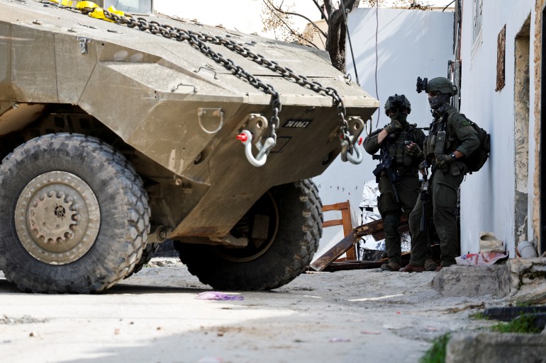 8654123ss-1741897007 جنين - الضفة الغربية Israeli soldiers stand next to a military vehicle during an Israeli raid in Jenin, in the Israeli-occupied West Bank, March 4, 2025. REUTERS/Raneen Sawafta
