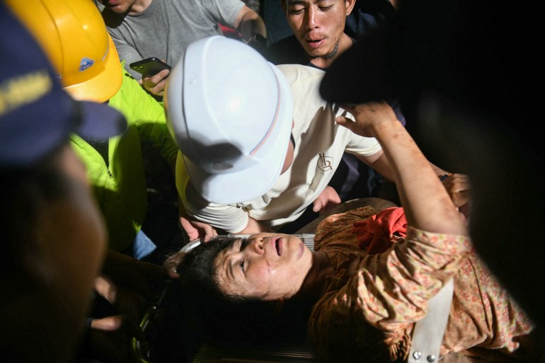 afp-609661906_f3c6cc-1743258294 TOPSHOT - Ye Aung (top) accompanies his wife Phyu Lay Khaing on their way to the hospital after she was rescued from the rubble of the collapsed Sky Villa Condominium apartment building in Mandalay on March 29, 2025, a day after an earthquake struck central Myanmar.