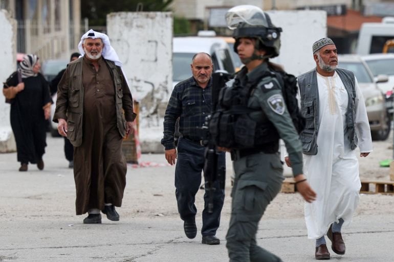 doc-388p6y2-1743155317 TOPSHOT - An Israeli border guard walks past Palestinian Muslims marching towards an army checkpoint in Bethlehem, in the occupied West Bank, on March 28, 2025, as worshippers head to the Al-Aqsa Mosque compound in Jerusalem's Old City for the last Friday prayers of the holy fasting month of Ramadan. (Photo by HAZEM BADER / AFP)
