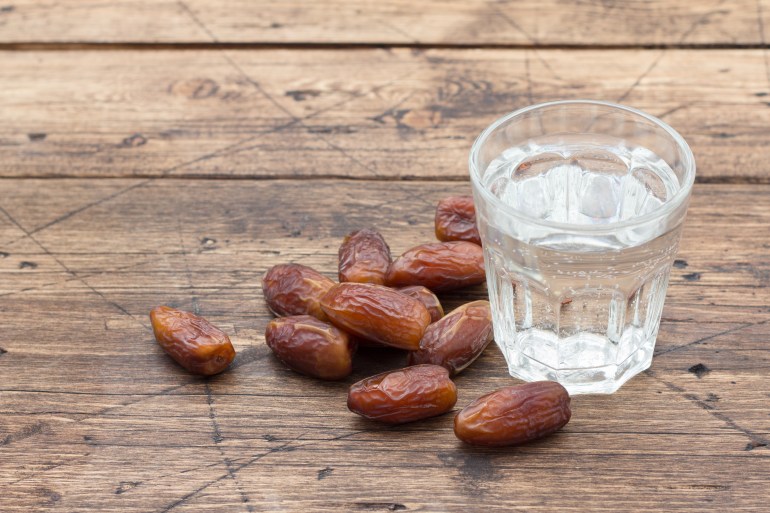 gettyimages-1148060571-1741591405 Dried dates fruits and a glass of water on a wooden table. Traditional fast breaking, Muslims evening meal during holy Ramadan
