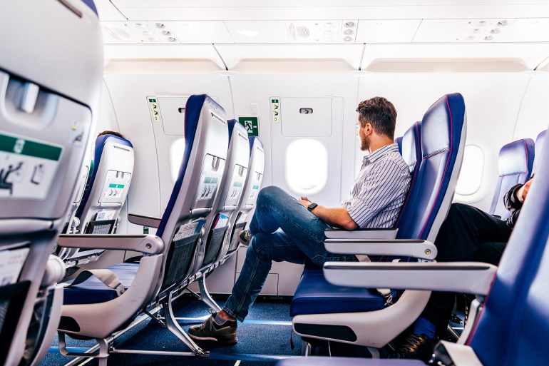 Male passenger in smart casual clothing flying in the exit row on an airplane - stock photo