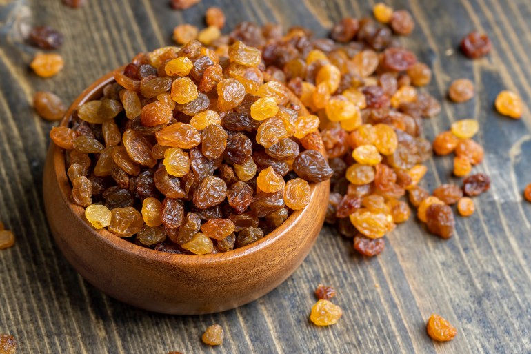Dried yellow golden raisins on a board, a pile of hard sweet and dry raisins for dessert; Shutterstock ID 2314008909; purchase_order: aj; job: ; client: ; other: