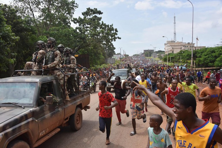 002-2 People celebrate in the streets with members of Guinea's armed forces after the arrest of Guinea's president, Alpha Conde, in a coup d'etat in Conakry, September 5, 2021. - Guinean special forces seized power in a coup on September 5, arresting the president and imposing an indefinite curfew in the poor west African country. "We have decided, after having taken the president, to dissolve the constitution," said a uniformed officer flanked by soldiers toting assault rifles in a video sent to AFP. (Photo by CELLOU BINANI / AFP) (Photo by CELLOU BINANI/AFP via Getty Images)