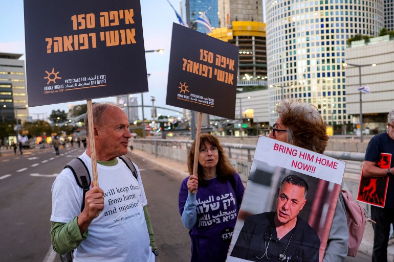 08-2-1743937806 A demonstrator holds a sign depicting Israeli-detained Palestinian paediatrician Hussam Abu Safiya, director of the Kamal Adwan Hospital in northern Gaza's Jabalia, while standing with others gathering during an anti-government protest against the death of Gaza aid workers outside the Israeli Defence Ministry headquarters in central Tel Aviv on April 5, 2025. Israeli forces launched a ground offensive in Gaza City, the military said on April 4, after renewed military operations in March ended a short-lived truce in its war with Hamas. Israel has since expanding its operations pushed to seize territory in the Gaza Strip in what it said was a strategy to force militants to free hostages still in captivity. (Photo by Jack GUEZ / AFP)