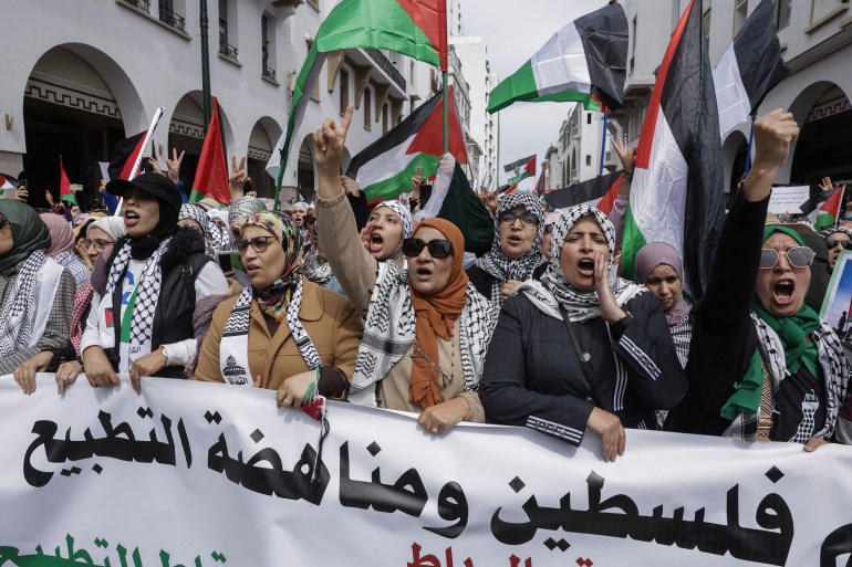 afp_67fbd52bef2b-1744557355 Women lift a banner and chant during a national march in support of Palestinians and against Morocco's normalisation of ties with Israel, in the capital Rabat on April 6, 2025. (Photo by Abdel Majid BZIOUAT / AFP)