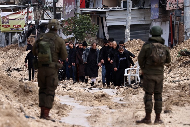 afp__20250210-1744618889 Israeli soldiers keep watch as Palestinians leave their homes for safety during a raid by the army in the Nur Shams refugee camp near Tulkarem in the occupied West Bank on February 10, 2025. (Photo by Zain JAAFAR / AFP)