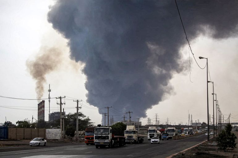 d8a8d986d8afd8b1-d8b9d8a8d8a7d8b3-d8a5d98ad8b1d8a7d9866-1745672715 A thick plume of smoke billows as motorists drive their vehicles along a highway near the source of an explosion at the Shahid Rajaee port dock southwest of Bandar Abbas in the Iranian province of Hormozgan on April 26, 2025. Several containers exploded on April 26 at Iran's largest commercial port, authorities said, causing a major blast and fire, and leaving hundreds injured. Shahid Rajaee, more than 1,000 kilometres (620 miles) south of the capital, is the most advanced container port in Iran, according to the official IRNA news agency. (Photo by Mohammad Rasole MORADI / IRNA / AFP)