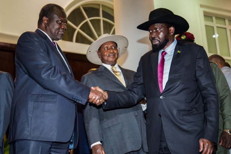 President of South Sudan, Salva Kiir (R) shakes hands with arch-rival South Sudan's opposition leader Riek Machar (L) during peace talks at Uganda's statehouse in Entebbe where they were received by Ugandan President Yoweri Museveni (C) on July 7, 2018. (Photo by SUMY SADURNI / AFP)