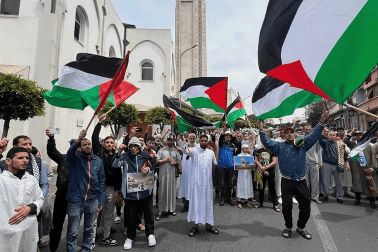d985d8bad8b1d8a8-1744404227 أشخاص يرفعون أعلام فلسطين خلال مسيرة لدعم الفلسطينيين في المغرب