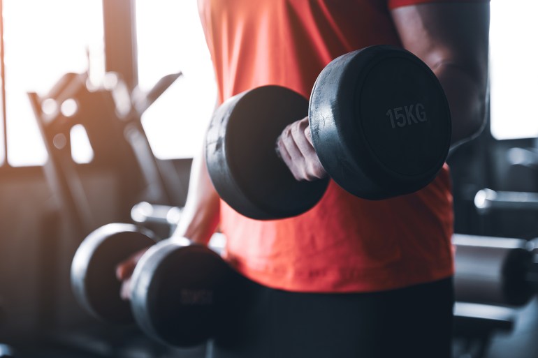 cropped image of unrecognisable man working out with dumbbell. Heavy weight exercise