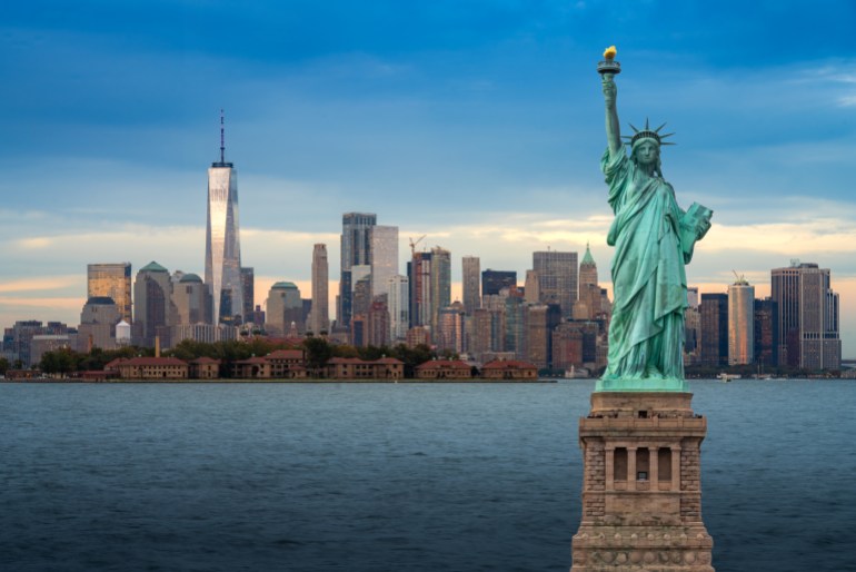 gettyimages-1198617190-1744696970 The statue of Liberty with Downtown New York skyline panorama with Ellis Island in the foreground at night in New York City, USA.