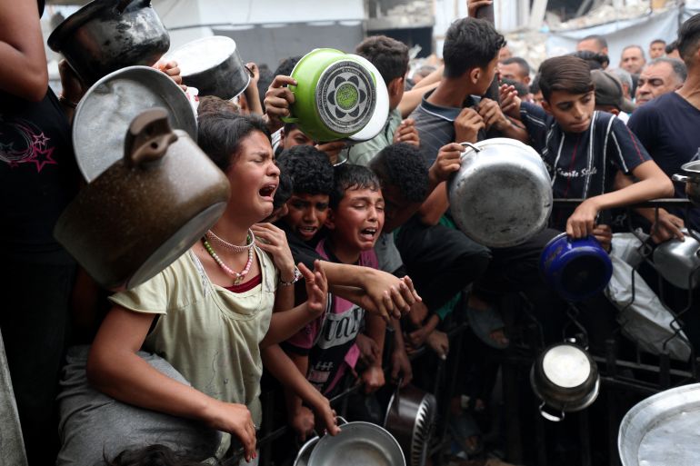 reuters_680e002e-1745748014 Children react as Palestinians wait to receive food cooked by a charity kitchen, in Beit Lahia, northern Gaza Strip, April 24, 2025. REUTERS/Mahmoud Issa