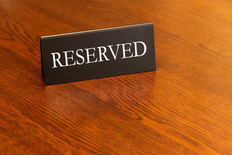 shutterstock_2437632219-1745160574 There is a sign on the wooden table indicating that this is a reserved seat.; Shutterstock ID 2437632219; purchase_order: aj; job: ; client: ; other: