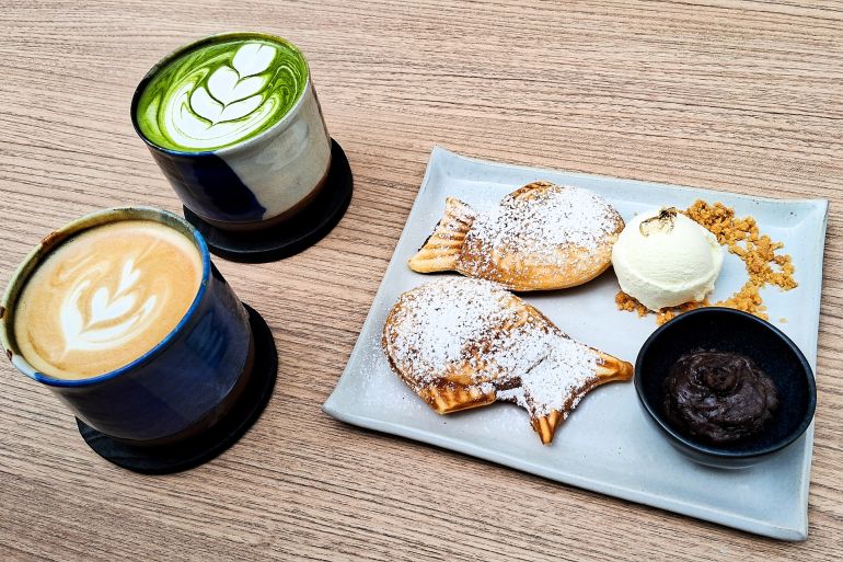 A delicious snack of a cup of hot latte, a cup of green tea, and a plate of fish-shaped cakes (Taiyaki) on the wooden table.; Shutterstock ID 2499537753; purchase_order: س; job: س; client: س; other: س