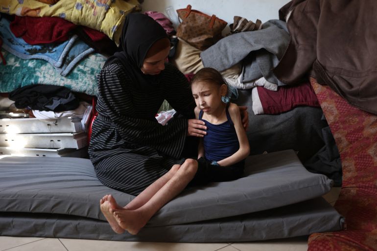 afp_681874c71979-1746433223 Shuruq Ayyad consoles her 12-year-old daughter Rahaf, who is suffering from malnutrition, at a school-turned-shelter in al-Rimal in central Gaza City on May 4, 2025.