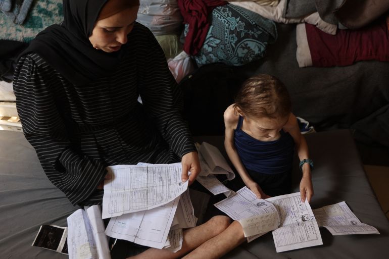 afp_681874e10c15-1746433249 Shuruq Ayyad and her 12-year-old daughter Rahaf, who is suffering from malnutrition, look at medical reports at a school-turned-shelter in al-Rimal in central Gaza City on May 4, 2025.