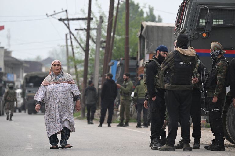 afp_681b04cef406-1746601167 Indian security personnel stand guard as a woman walks along a road in Wuyan near Indian-administered Kashmir's main city of Srinagar on May 7, 2025.