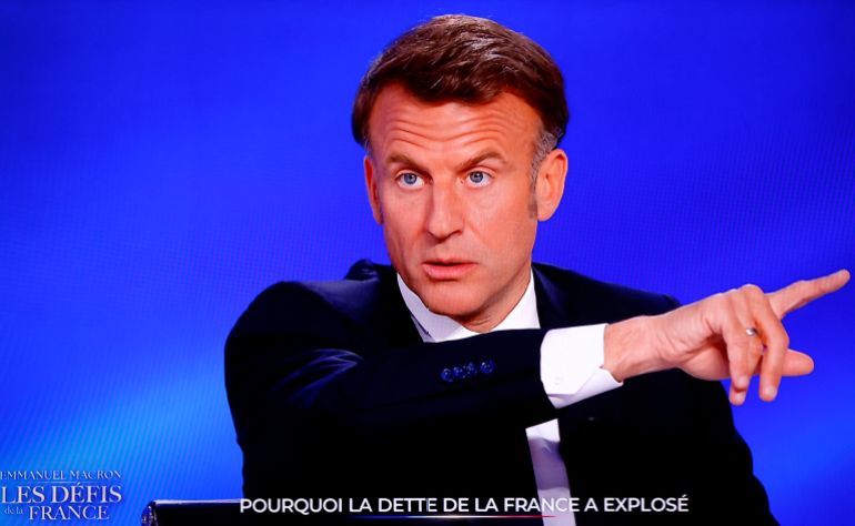 France's President Emmanuel Macron appears on the main control room screens of the French channel TF1 during his guest appearance on a special program in Saint-Denis, north of Paris, on May 13, 2025.