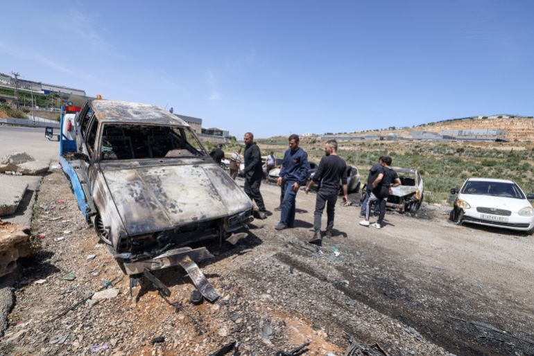 afp_6828d7e9205f-1747507177-1 Palstinian men check burnt out vehicles in the Barkan Industrial area, near Salfit in the occupied West Bank, on May 16, 2025, after more than 17 Palestinian workers' cars were reportedly set on fire by Israeli settlers the night before.