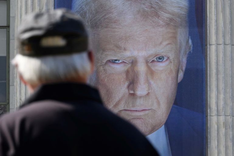 A pedestrian passes by a banner showing an image of US President Donald Trump hangs on the side of a US Department of Agriculture building in Washington, DC, on May 16, 2025.