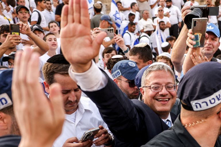 afp_683581f35c55-1748337139 Israeli Minister of National Security and far-right politician Itamar Ben-Gvir, surrounded by Israeli policemen, waves to other right-wing activists gathering outside the Damascus Gate of the walled Old City of Jerusalem on May 26, 2025, during a flag march for Jerusalem Day, commemorating the Israeli army's 1967 capture of the city's eastern sector during the Arab-Israeli war.