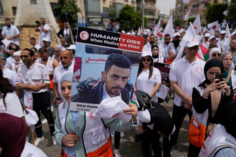 ap_6821de9673868-1747050134 Paramedic hold posters with names and pictures of fellow relief workers who lost their lives in the line of humanitarian duty, during a symbolic funeral for 48 fallen Palestinian Red Crescent Society members during the Israel Hamas war in Gaza, according to a PRCS statement, marking the World Day of Red Cross and Red Crescent, in the West Bank city of Ramallah Monday, May 12, 2025. (AP Photo/Nasser Nasser)