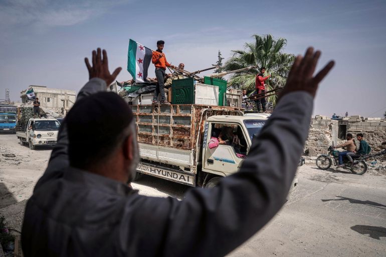 ap_683075f6b904e-1748006390 A man greets trucks carrying displaced families as they return, supported by an NGO, to their village after more than five years in the Atmeh camps near the Syrian-Turkish border, in Kafr Sijna, south of Idlib, Syria, Sunday, May 18, 2025. (AP Photo/Ghaith Alsayed)