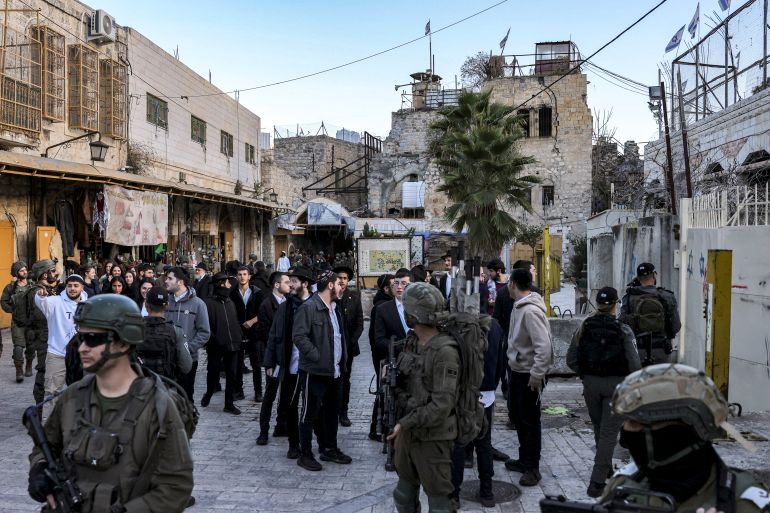 d8a8d98ad8ab-2-1735467450 Israeli army soldiers stand guard as Israeli Jewish settlers tour the old market in the city of Hebron in the occupied West Bank on December 28, 2024. (Photo by HAZEM BADER / AFP)