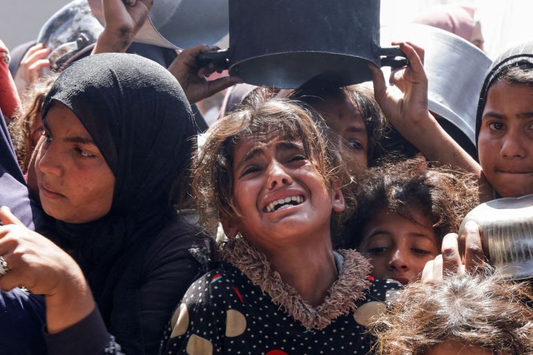 طفلة غزية ملامحها تصرخ قبل صوتها، تحاصرها الأواني الفارغة والأجساد المتعبة، في طابور طويل للحصول على وجبة لا تكفي. عيونها المرتعبة ترسم مأساة جوع ممنهج يطال الأطفال قبل الكبار.