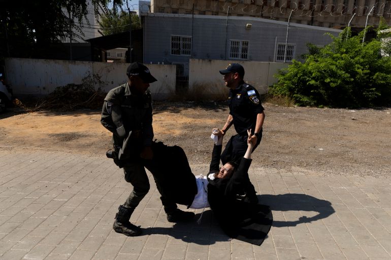 getty_682349583d-1747143000 RAMAT GAN, ISRAEL - AUGUST 5: Police officers disperse an an Ultra Orthodox Jewish protester during a demonstration against drafting to the Israeli military near a recruitment base on August 5, 2024 in the Tel HaShomer area of Ramat Gan, Israel. Hundreds of Ultra-Orthodox men who were previously exempted from military service were due to arrive at the recruitment office here today, following a Supreme Court ruling that ended the exemption for yeshiva students. (Photo by Amir Levy/Getty Images)