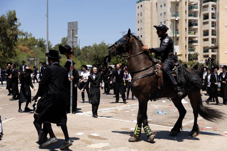 getty_682349a163-1747143073 RAMAT GAN, ISRAEL - AUGUST 5: Ultra-Orthodox Jewish men clash with mounted police officers during a demonstration against drafting to the Israeli military near a recruitment base on August 5, 2024 in the Tel HaShomer area of Ramat Gan, Israel. Hundreds of Ultra-Orthodox men who were previously exempted from military service were due to arrive at the recruitment office here today, following a Supreme Court ruling that ended the exemption for yeshiva students. (Photo by Amir Levy/Getty Images)