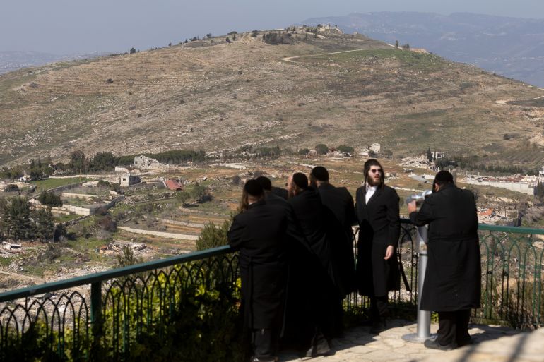 MISGAV AM, ISRAEL - FEBRUARY 18: Ultra-Orthodox Jewish men look along the the Lebanese village of Odaisseh as seen from a position on the Israeli side of the border on February 18, 2025 in Misgav Am, Israel. Despite troops withdrawal from Southern Lebanon, Israeli military remain at five Southern Lebanese posts. (Photo by Amir Levy/Getty Images)