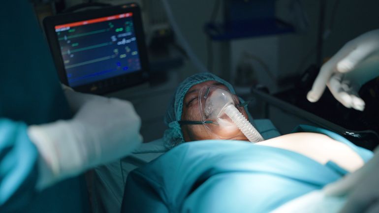 Dead patient surgeon doctor covering face on bed finished operate in emergency room at hospital, surgery failed concept