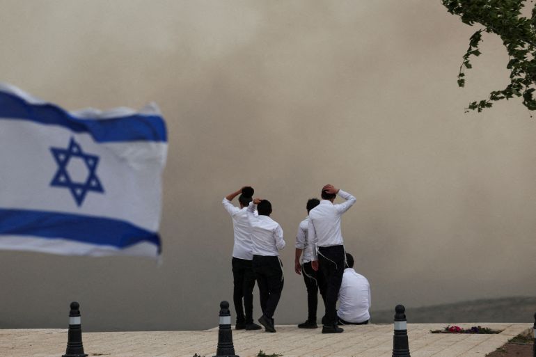 People look at smoke as wildfires broke out in central Israel, in Neve Ilan