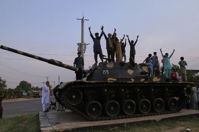 Pakistani people flashing victory signs stand over a tank as they celebrate after the ceasefire between Pakistan and India, in Multan on May 10, 2025. Pakistan and India agreed to a full and immediate ceasefire on May 10 after days of deadly jet fighter, missile, drone and artillery attacks, the news surprisingly announced by US President Donald, who congratulated them on using "common sense". (Photo by Shahid Saeed MIRZA / AFP) (Photo by SHAHID SAEED MIRZA/AFP via Getty Images)