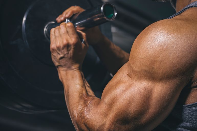 Bodybuilder preparing a barbell on a power rack in gym