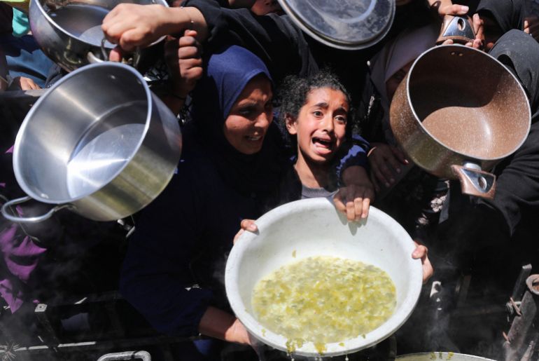 A girl reacts, as Palestinians wait to receive food cooked by a charity kitchen, in Beit Lahia, northern Gaza Strip, May 8, 2025. REUTERS/Mahmoud Issa