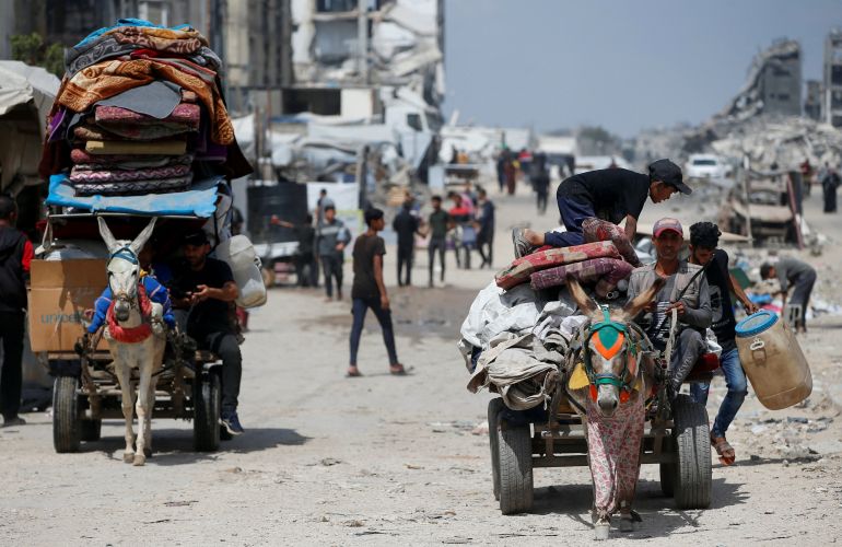 Palestinians make their way with belongings as they flee their homes after the Israeli military issued orders of evacuation from the northern Gaza Strip, May 22, 2025. REUTERS/Mahmoud Issa