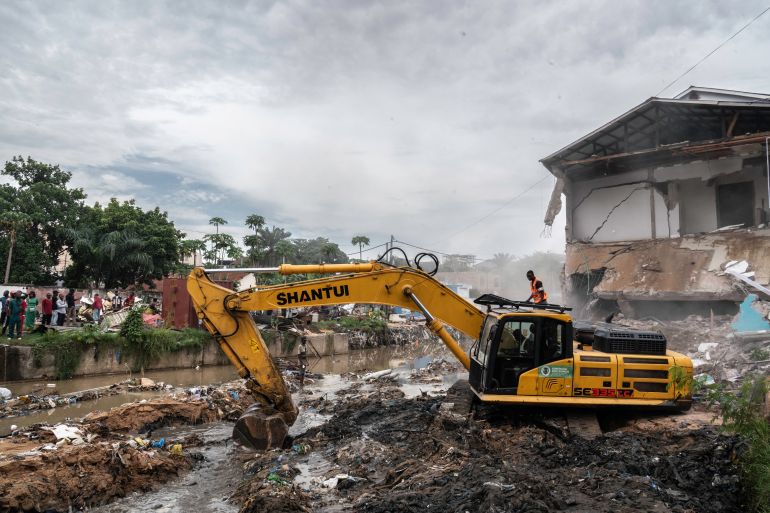 vf-4-1746964833 An excavator designed to demolish anarchic buildings manuevers in a river in Kinshasa, Democratic Republic of Congo, on May 8, 2025, after authorities in the DRC decided to demolish all unauthorised buildings in flood-prone areas following the floods of April 5, 2025 which killed around thirty people. (Photo by Glody MURHABAZI / AFP)