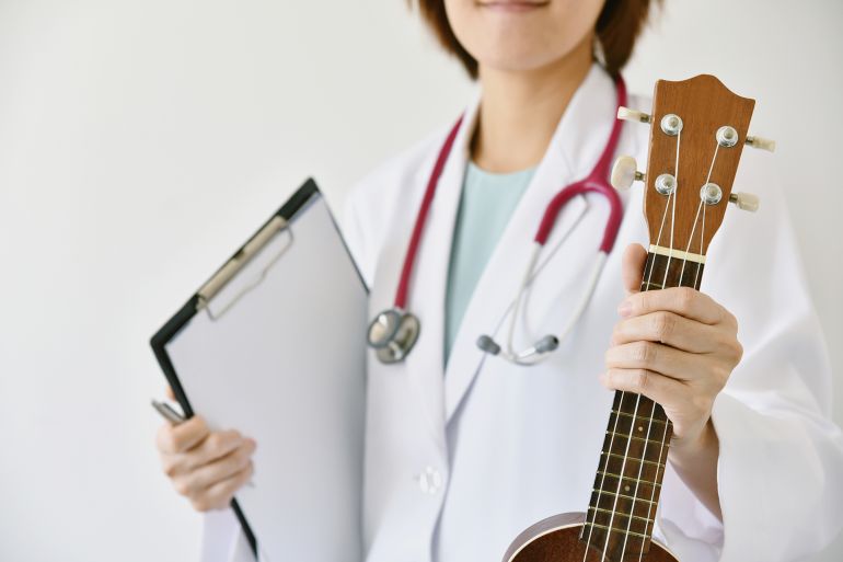 dfg5ty-1748960427 Doctor hand holding ukulele (musical instrument), Music therapy concept. (Selective Focus)