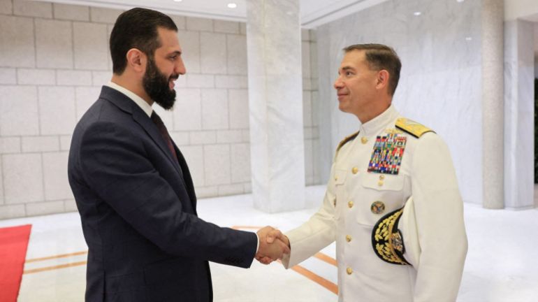 afp_68c476161650-1757705750 A handout picture released by the official Syrian Arab News Agency (SANA) shows Syria's interim President Ahmad Al-Sharaa (L) welcoming the new head of the US military's Central Command Admiral Brad Cooper ahead of their meeting in the Syrian capital Damascus on September 12, 2025.