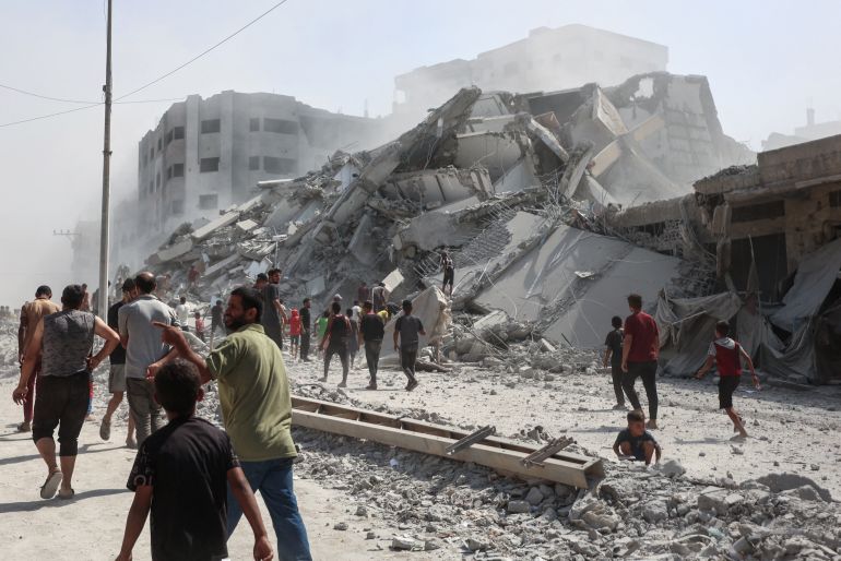 فلسطينيون يبحثون عن ناجين بين ركام برج الغفاري المدمر إثر قصف إسرائيلي عنيف (الفرنسية)