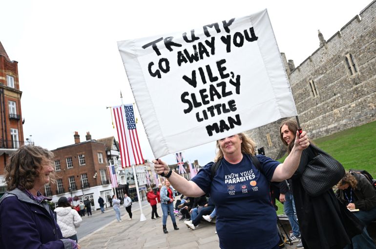 A demonstrator wearing an anti-Trump t-shirt, while holding a banner as they protest near Windsor Castle, in Windsor, on September 17, 2025, during US President Donald Trump's second State Visit to the UK.