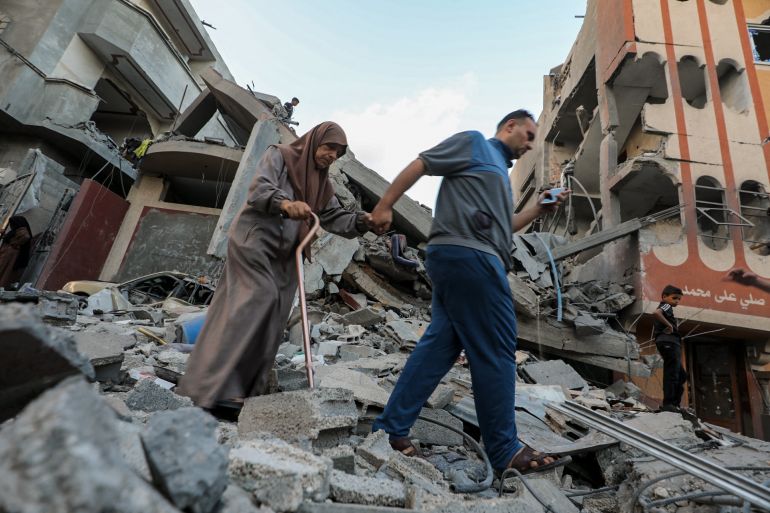 A Palestinian man and a woman walk above the rubble of a building hit by an Israeli strike in the Nuseirat refugee camp in the central Gaza Strip, on September 25, 2025, as Israel presses its air and ground offensive to capture the nearby Gaza City.