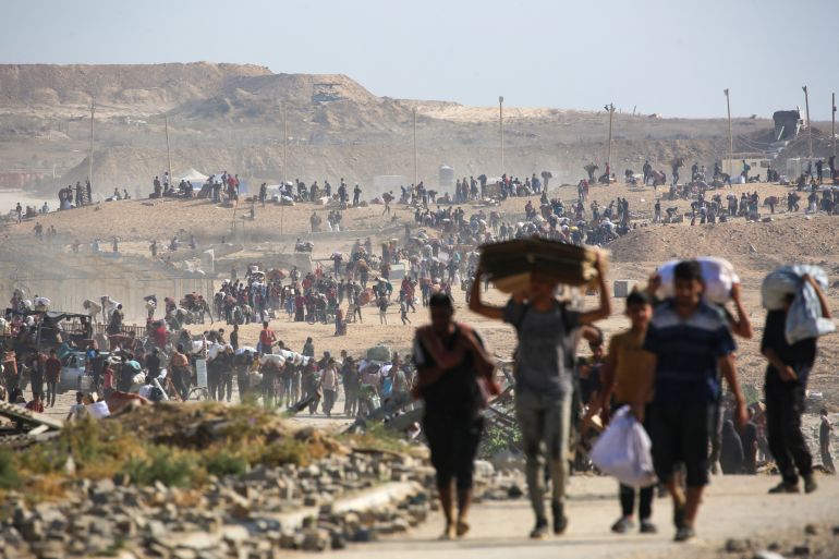 TOPSHOT - People walk with bags of humanitarian aid they received at a distribution centre run by the US and Israeli-backed Gaza Humanitarian Foundation (GHF), at the so-called "Netzarim corridor", in Nuseirat in the central Gaza Strip, on September 26, 2025.