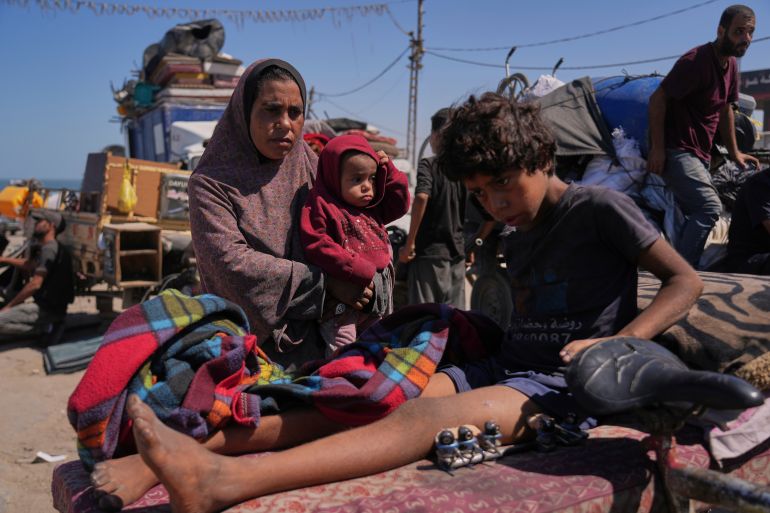 FILE - Amal Al-Qishawi, follows her injured son, Yasser, 11, carried on a bicycle by his father Rafiq Al-Qishawi, as they flee northern Gaza Strip walking along the coastal road, near Wadi Gaza, Saturday, Sept. 20, 2025. (AP Photo/Abdel Kareem Hana)