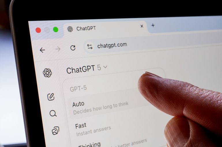 Finger points at ChatGPT 5 model selector on chatgpt.com, showing Auto, Fast and Thinking modes on a laptop screen. Stafford, United Kingdom, August 21, 2025